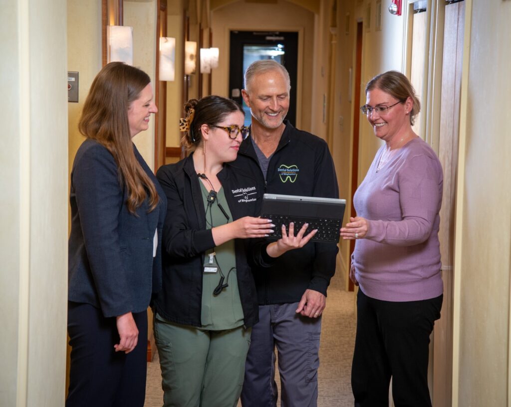 Binghamton Hybridge dental solutions full arch dental implants doctors and hygienists looking at ipad